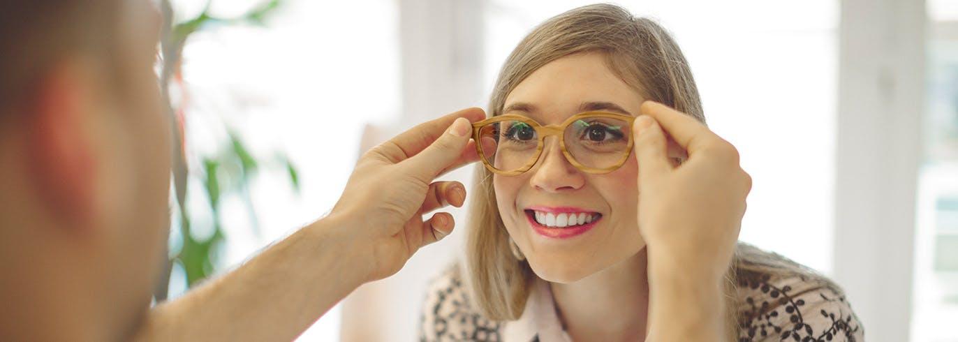 Jeune femme essayant des lunettes chez un opticien